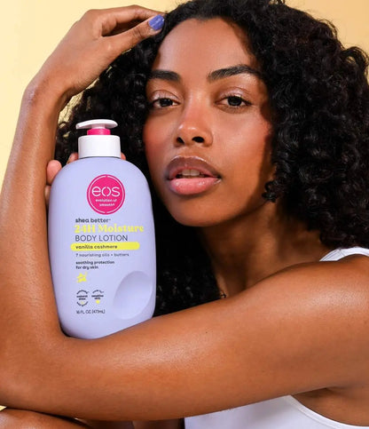 Woman holding an EOS body lotion bottle against a beige background