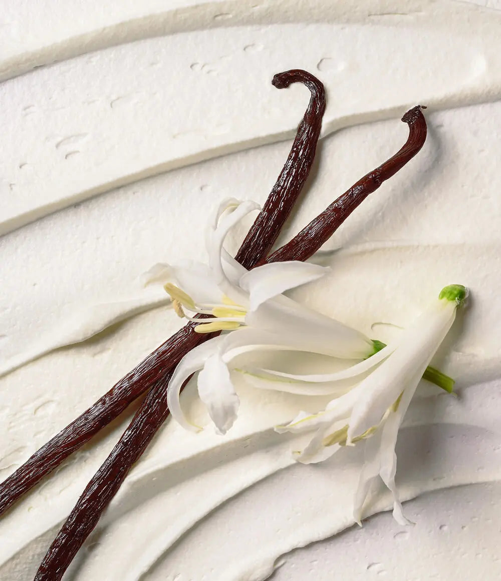 Vanilla beans and vanilla flower on a light wooden surface